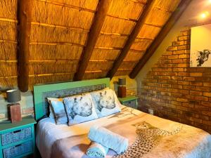 a bedroom with a large bed with a brick wall at Indlovu Inn in Marloth Park +12 photos