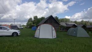 a group of tents and a car parked in a field at Loopre Vesiveski puhketalu in Loopre +6 photos