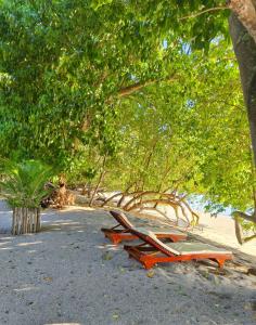 a beach chair laying on the sand under a tree at Air Wontu in Moyo Island +27 photos