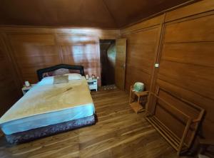 a bedroom with a bed with wooden walls and wooden floors at Air Wontu in Moyo Island