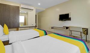 a hotel room with two beds and a tv at Hotel G Square in Vijayawāda