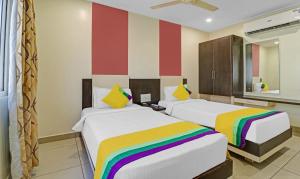 two beds in a room with a colorful striped wall at Hotel G Square in Vijayawāda