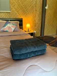 a pile of towels sitting on top of a bed at Alisa Villa, Ubon Cottage in Ban Pla Duk