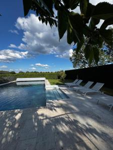 a swimming pool with white lounge chairs next to it at Les gîtes de la Grange de Léonie - jacuzzis privatifs et Piscine in Vierzon
