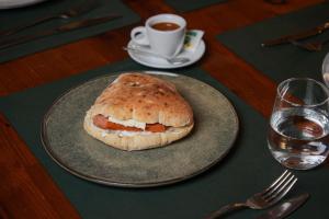 a plate with a sandwich on a table with a cup of coffee at Velor Boutique Hotel in Tirana
