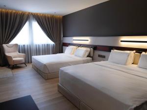 a hotel room with two beds and a chair at Merchant Hotel in George Town