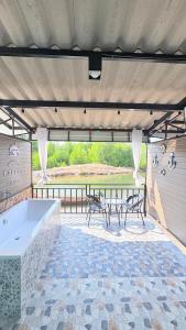 a large patio with a tub and a table and chairs at Kohlibong forest house in Trang
