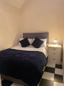 a bed with black and white sheets and a night stand at Lodge 1, The Grange in Wick