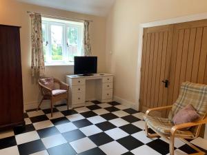 a room with a checkered floor with a tv and a chair at Lodge 1, The Grange in Wick