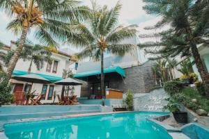 a swimming pool in front of a house with palm trees at Aleyra Hotel and Villa's Garut in Garut