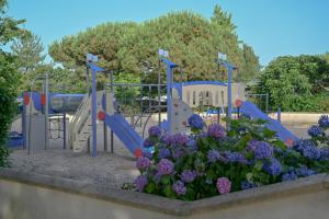 a park with a playground with a slide and flowers at Camping Domaine du Morbihan in Ambon