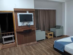 a hotel room with a bed and a tv and a room at Cross Bill Beach Resort in Havelock Island