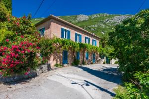 a building with blue shutters and flowers on a street at Villa Balic in Gruda