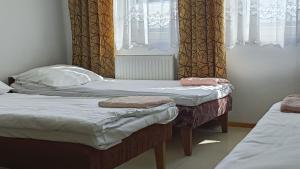 two twin beds in a room with a window at Hostel Wólka Kosowska z prywatnymi łazienkami in Wólka Kosowska