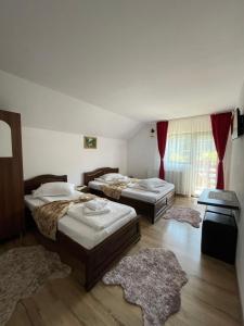 three beds in a room with rugs at Casa Mona in Arieşeni