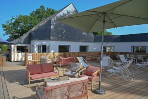 a patio with chairs and an umbrella on a deck at Camping Domaine du Morbihan in Ambon +31 photos