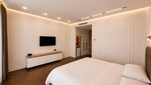 a bedroom with a white bed and a tv on the wall at Hotel Zerbulaq in Taraz