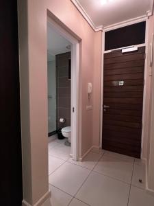 a bathroom with a toilet and a wooden door at The Residences at Crystal Towers in Cape Town