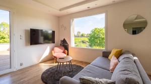 a living room with a couch and a large window at Les sapins verts - vue haras in Saint Lo