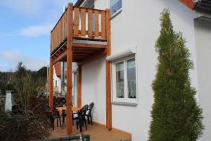a wooden deck with a table and chairs on a house at Ferienwohnungen am Wald in Lütow