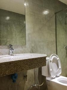 La salle de bains est pourvue d'un lavabo, de toilettes et d'un miroir. dans l'établissement Nai Suan Inn, à Ban Doem Bang