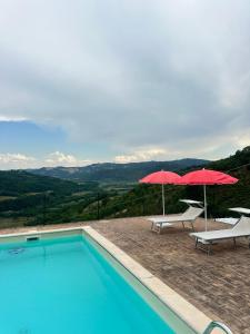 a swimming pool with two umbrellas and two chairs at Villa Sant' Andrea in Gubbio