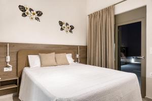 a bedroom with a white bed with two butterflies on the wall at Azzurro Luxury Villas in Kolymbia