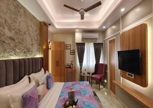 a hotel room with a bed and a flat screen tv at Atlantiis Suites By Signature StayZ Girjaghar Near Vishwanath Temple in Varanasi +19 photos
