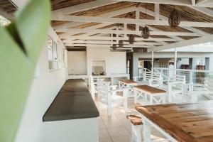 a restaurant with white tables and white stools at Treetops, Amblewood Guesthouse in Kenton on Sea