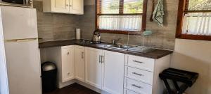 a small kitchen with white cabinets and a sink at Riverman Cabin Country Lodge - Tonteldoos in Tonteldoos +173 photos