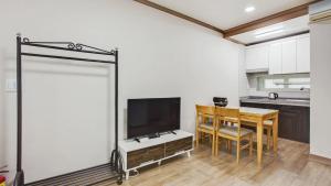 a kitchen with a table and a television in a room at Gapyoeng New Cheongpyeong Pension in Gapyeong