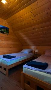 two beds in a room with wooden walls at Domek na Hubce 1 Blisko Velo Czorsztyn in Maniowy