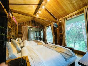 a bedroom with two beds and a large window at Lam Ecolodge Mu Cang Chai in Nam Khat