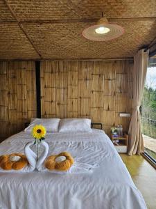 a bed with two towels and a vase with a sunflower on it at Mon Ngo misty haven B4 in Ban Mae Ta Man