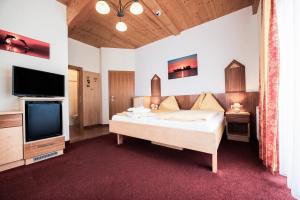a bedroom with a bed and a flat screen tv at Hotel Garni Zerza in Tröpolach