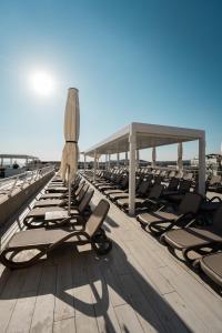 eine Reihe Liegestühle und ein Sonnenschirm am Strand in der Unterkunft Santana Hotel & SPA in St Paul's Bay