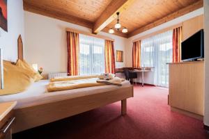 a hotel room with a bed and a television at Hotel Garni Zerza in Tröpolach