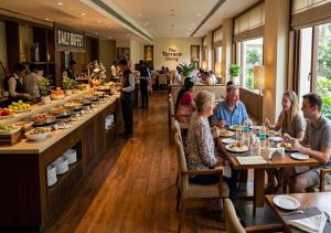a group of people sitting at tables in a restaurant at Atlantiis Suites By Signature StayZ Girjaghar Near Vishwanath Temple in Varanasi