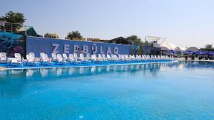 a large swimming pool with blue chairs at Hotel Zerbulaq in Taraz +3 photos