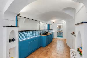 a kitchen with blue cabinets and a tile floor at Starhost - RICORDO DEL CAPITANO, Atrani hidden gem Walking distance from Amalfi & Beach in Atrani