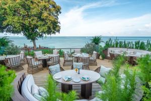 a patio with tables and chairs and the ocean at Cape Panwa Hotel Phuket in Panwa Beach