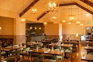 a restaurant with wooden tables and chairs and chandeliers at Fitzgeralds Woodlands House Hotel in Adare