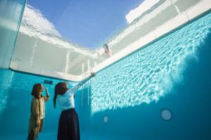 two girls are standing next to a swimming pool at House Hotel Kenrokuzaka in Kanazawa