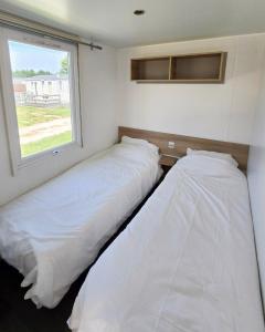 two beds in a small room with a window at Parc St Vincent in La Celle-sous-Gouzon