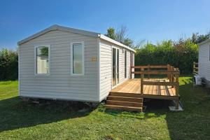 a white tiny house with a porch and a wooden deck at Parc St Vincent in La Celle-sous-Gouzon
