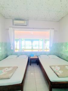 two beds in a room with a window at Đào Huỳnh Motel in Nam Du