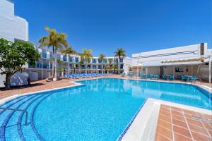 a large swimming pool with palm trees and a building at BLUESEA Jandia Luz in Morro del Jable