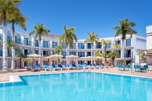 a swimming pool in front of a hotel with palm trees at BLUESEA Jandia Luz in Morro del Jable