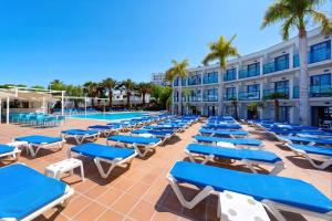 a row of blue lounge chairs next to a swimming pool at BLUESEA Jandia Luz in Morro del Jable +27 photos