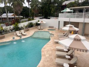 a pool with chairs and umbrellas in a hotel at Port Douglas Penthouse Suite in Port Douglas